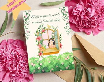 May include: A white card with a watercolor illustration of a window with a woman looking out. The window is surrounded by pink flowers and green leaves. The card has the text "El dia en que tu naciste, nacieron todas las flores" in Spanish.