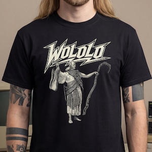 Könnte beinhalten: Schwarzes T-Shirt mit einem weißen Grafikdesign einer gewandeten Figur, die eine Peitsche hält, und dem Wort "WOLOLO" in einer stilisierten Schriftart. Das Design bildet einen auffälligen Kontrast zum dunklen Stoff.