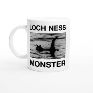 Peut inclure: Mug en céramique blanche avec une image en noir et blanc du monstre du Loch Ness. Le mug porte l'inscription "LOCH NESS MONSTER" en noir. L'image montre le monstre dans l'eau.