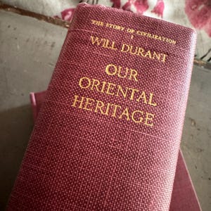 May include: A white ceramic mug with a black handle and the text "But First, Coffee" in a bold, black font. The mug is sitting on a wooden surface. The mug is approximately 4 inches tall.