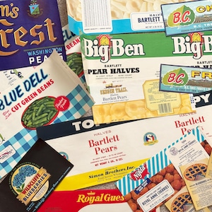 May include: A collection of vintage food packaging labels, including "Denison's Crest" peas, "Blue Dell" green beans, "Big Ben" pear halves, and "Royal Anne Cherries." The labels feature colorful graphics and text.