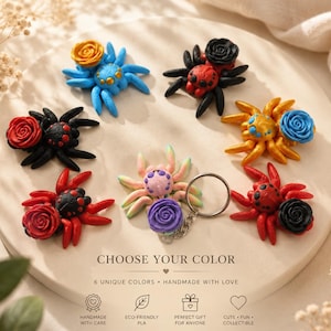Puede incluir: Colección de figuras de arañas hechas a mano, coloridas, con detalles de rosas, dispuestas sobre una superficie circular blanca. Las arañas son de varios colores, incluyendo azul, rojo y amarillo. El texto "CHOOSE YOUR COLOR" es visible.