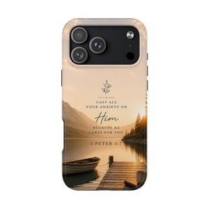 May include: A phone case with a sunset lake scene, a wooden pier, and a boat. The case displays the text "CAST ALL YOUR ANXIETY ON Him BECAUSE HE CARES FOR YOU. 1 PETER 5:7". The case is tan and has a camera cutout.