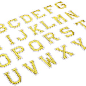 May include: A selection of gold embroidered alphabet letters with white borders, displayed on a white background. The letters are in a traditional serif font, ideal for customising items.