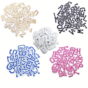 May include: A collection of embroidered letter patches in gold, black, silver, blue, and pink. Each patch displays a different letter of the alphabet. These patches are suitable for personalising clothing, bags, or other fabric items.