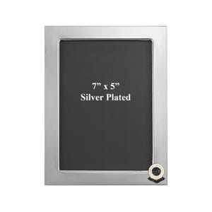 Può includere: Cornice per foto argentata con un passepartout nero e un'apertura di 17,8 cm x 12,7 cm. La cornice ha un piccolo emblema rotondo argentato con un design di pallone da calcio bianco e nero nell'angolo in basso a destra.