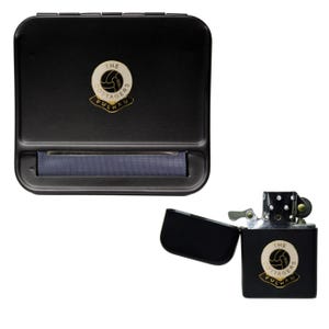 May include: A black rolling box and a black lighter. Both items feature a circular emblem with the text "THE COTTAGERS FULHAM" in a gold and white design. The lighter is open, revealing its interior.