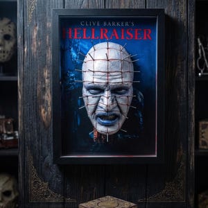 May include: A framed 3D wall art piece featuring the character Pinhead from Clive Barker's Hellraiser, with a pale face, blue lips, and metal pins protruding from the skin. Below the frame sits a wooden puzzle box with intricate gold engravings.