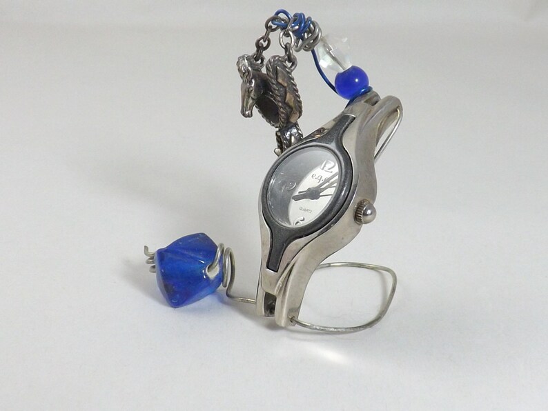 Miniature table clock to please rodeo lover or ranch person watchface. featuring a charm of a horse within a spur on a silver e.g.o