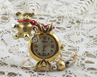 Miniature gold table clock for any nook or a child's bedside featuring gold teddy bear with jewel and old fashioned fancy watchface.