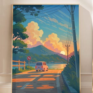 以下が含まれることがあります： 額縁に入ったアートプリントは、夕焼けに向かって走る車の道路シーンを描いています。空は青からオレンジへのグラデーションで、ふわふわの雲があります。背景には山脈と水が見えます。