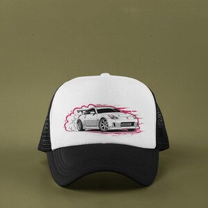May include: A black and white trucker hat with a white front panel featuring a graphic of a silver sports car drifting, with pink smoke and accents. The hat has a black brim and mesh back.