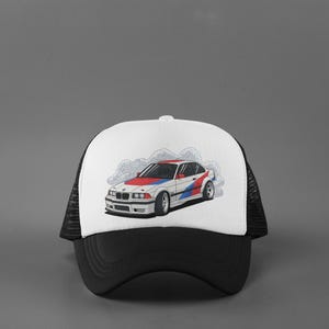 May include: Black and white trucker hat with a white front panel featuring a graphic of a white car with red, white, and blue racing stripes. The car is depicted with smoke, suggesting speed.