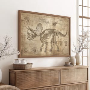 May include: A vintage-style illustration of a Triceratops skeleton with detailed anatomical markings. The image is printed on a beige paper and framed in a brown wood frame.