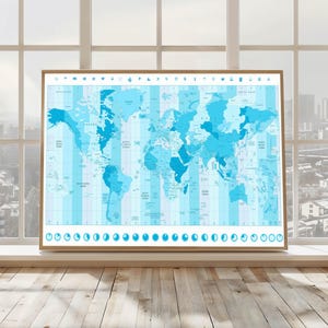 May include: A framed world map in shades of blue, showing time zones. The map has detailed country outlines and labels, set against a light blue background. The frame is light brown, and the map is displayed in front of a window.