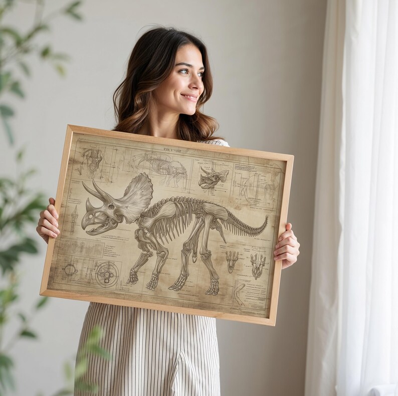 May include: A woman holds a framed print of a triceratops skeleton. The print is in a vintage style with a beige background and black lines. The triceratops skeleton is in the center of the print and is surrounded by diagrams and text.