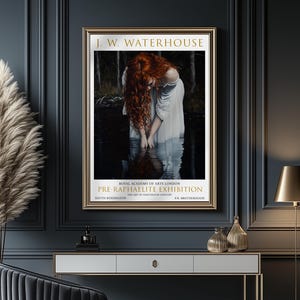 May include: A framed art print of a J.W. Waterhouse painting. The image shows a woman with red hair in a white dress, standing in water. The gold frame surrounds the artwork, with text for a Pre-Raphaelite exhibition.
