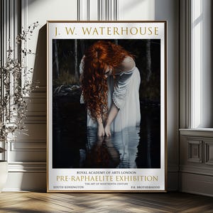 May include: A framed art print of a J.W. Waterhouse painting. It shows a woman with flowing red hair in a white dress, standing in water. The gold frame surrounds the artwork, with text reading "PRE-RAPHAELITE EXHIBITION".