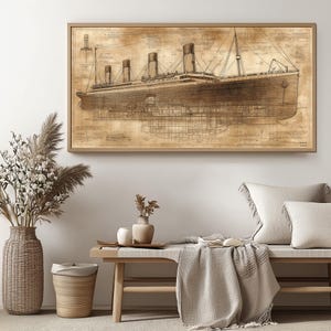 May include: A sepia-toned blueprint style illustration of the RMS Titanic, a large passenger liner, with detailed lines and markings. The image is framed and displayed on a wall above a wooden bench with a throw blanket.