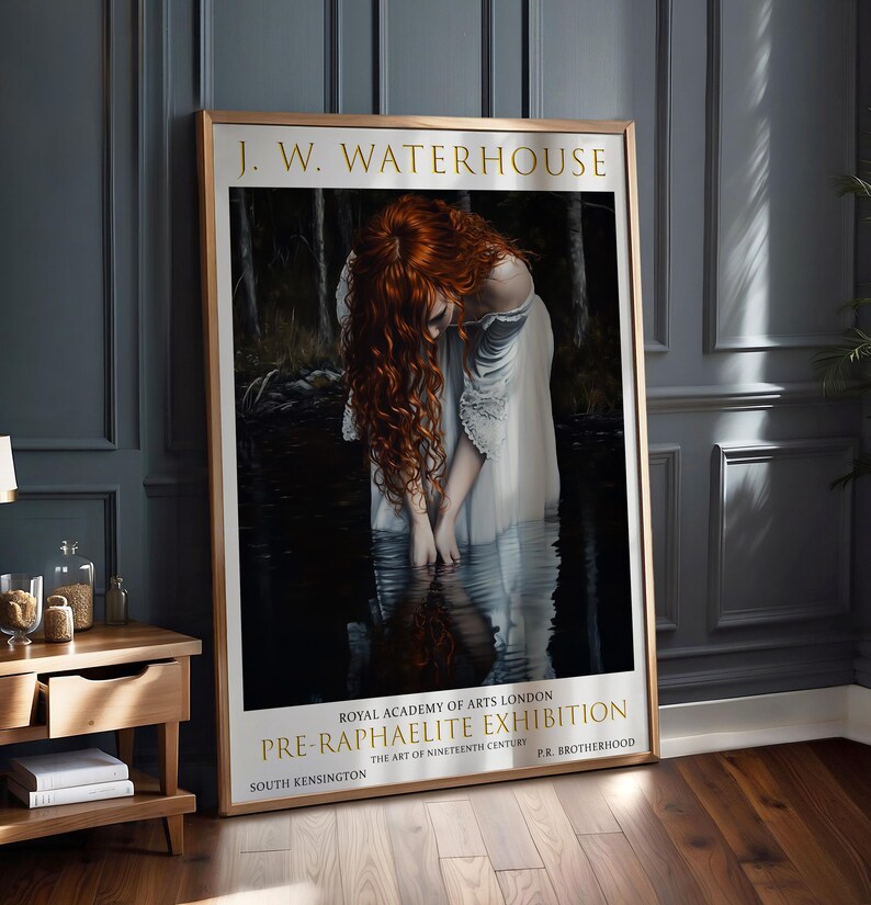 May include: A framed art print of a J.W. Waterhouse painting. The image shows a woman with flowing red hair in a white dress, standing in water. The print includes text: "PRE-RAPHAELITE EXHIBITION" and "ROYAL ACADEMY OF ARTS LONDON".
