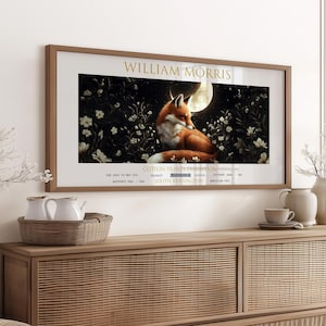Może przedstawiać: Ramka z plakatem reklamującym wystawę bawełnianych wydruków Williama Morrisa w Victoria and Albert Museum w South Kensington w Londynie. Plakat przedstawia stylizowaną ilustrację lisa siedzącego w oświetlonym księżycem lesie.