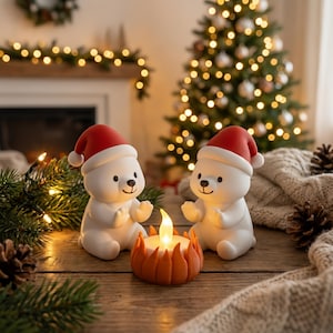 Op de afbeelding: Twee witte ijsbeerbeeldjes met rode kerstmutsen zitten op een houten oppervlak, aan weerszijden van een oranje kandelaar met een flikkerende vlam. Een kerstboom en slinger met lichtjes staan op de achtergrond, wat een feestelijke vakantiescène creëert.