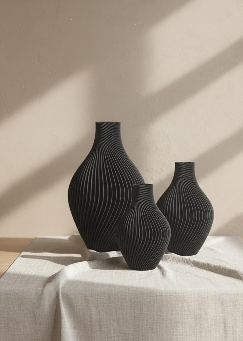 Może przedstawiać: Zestaw trzech ceramicznych kubk&oacute;w z nakrapianym, matowym wykończeniem. Kubki są w odcieniach kremu, jasnoszarym i ciemnoszarym. Każdy kubek ma prosty, minimalistyczny design, idealny do kawy lub herbaty.