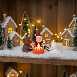 Kleine kerstscène op houten plank met Santa, rendier en smeltende sneeuwpop in een miniatuur-kerstdorp. Verlichte huisjes en sneeuwdecor maken dit handgemaakte stuk perfect voor een warme, sfeervolle kerstpresentatie.