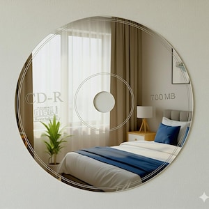 Puede incluir: Un espejo redondo con forma de disco CD-R, con detalles grabados que incluyen el texto "CD-R", "Compact Disc Rewritable" y "700 MB". El espejo refleja una escena de dormitorio con una cama, una mesita de noche y una ventana.