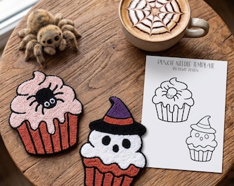 May include: Two punch needle cupcake patches, one with a spider and one with a witch hat, a fuzzy spider figurine, and a white paper punch needle template with the text PUNCH NEEDLE TEMPLATE by POKO DESIGN featuring two cupcake line drawings.