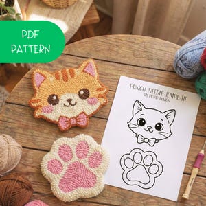 May include: A handmade orange and white cat face and pink paw rug, along with a punch needle template. The cat face has a pink bow tie and the text "PDF PATTERN" is in a green bubble. Yarn balls are in the background.