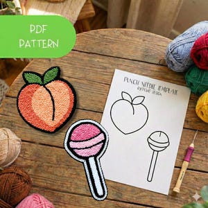 May include: A peach and lollipop punch needle pattern with the text "PDF PATTERN" on a green oval. The peach and lollipop are made with pink, orange, and white yarn. A paper with a peach and lollipop outline is also present.