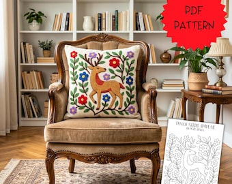 May include: A square throw pillow featuring a punch needle embroidery of a deer surrounded by colourful red, blue, and purple flowers and green leaves. A white paper sheet displays a black and white line art template of the same deer design.