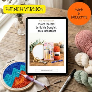 May include: A tablet displaying a punch needle guide, with craft supplies arranged around it. Includes an embroidery hoop with a colorful design, yarn, scissors, needles, and a pen. The tablet reads "Punch Needle: Le Guide Complet pour Débutants".