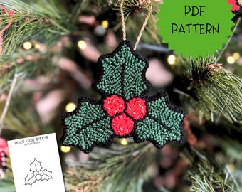 Op de afbeelding: Een punch needle ornament in de vorm van drie hulstbladeren en drie rode bessen met een zwarte rand en een gouden ophanglus. Een groene stervormige afbeelding toont PDF PATTERN. Een witte kaart toont een zwarte lijntekening PUNCH NEEDLE TEMPLATE.