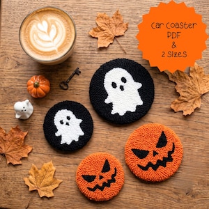 May include: Two round black coasters with white ghost designs and two round orange coasters with black jack-o'-lantern faces. The text car coaster PDF & 2 SizeS is visible. These tufted items are displayed alongside a coffee cup, a small pumpkin, a ghost figurine, a metal key, and dried autumn leaves.