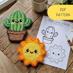 May include: Handmade cactus and sun-shaped punch needle coasters. The cactus is green with a brown pot, and the sun is yellow and orange. A paper with a cactus illustration and the text "PDF PATTERN" is also visible.
