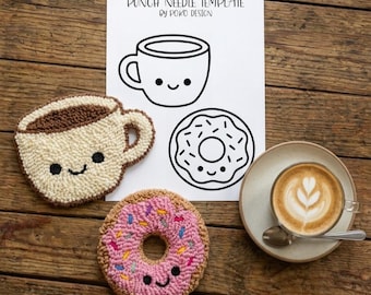 May include: A wooden table displays punch needle art of a coffee cup and donut, a latte, and a template. The punch needle art includes a smiling coffee cup and a donut with pink icing and sprinkles. The template reads "PUNCH NEEDLE TEMPLATE BY POKO DESIGN."