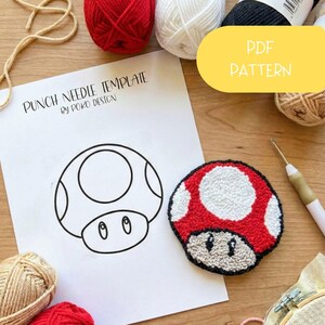 Könnte beinhalten: Ein rotes und weißes pilzförmiges Punch-Needle-Werk neben einer Vorlage mit dem Text "PUNCH NEEDLE TEMPLATE". Das Bild enthält auch Wollknäuel, ein Punch-Needle-Werkzeug und ein gelbes "PDF PATTERN"-Etikett.