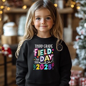 Può includere: Felpa nera con una grafica colorata che dice "Third Grade Field Day Fun Day 2025".