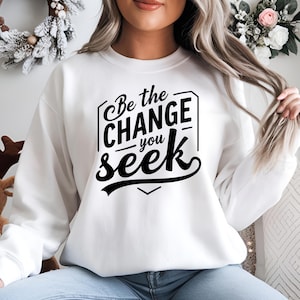 Peut inclure: Sweat-shirt blanc avec un texte noir qui dit "Be the change you seek".