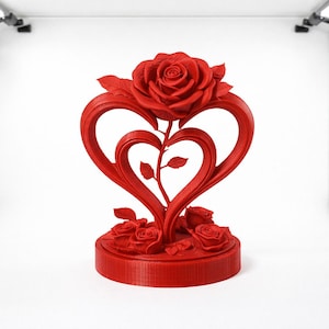 Op de afbeelding: Een helderrode decoratieve sculptuur met een rozen- en hartontwerp. De sculptuur heeft een grote roos aan de bovenkant, met twee in elkaar verweven harten en kleinere rozen aan de basis. Het stuk is gemaakt van een stevig materiaal en staat op een ronde basis.
