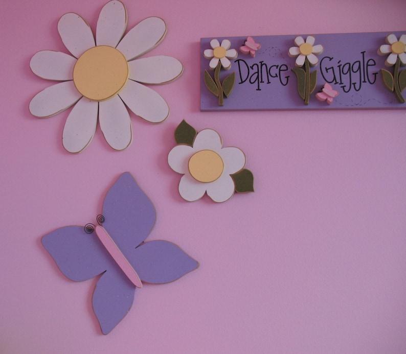 May include: Purple butterfly, white daisy with yellow centre, and a sign that reads "Dance Giggle" with pink butterflies on a pink background.