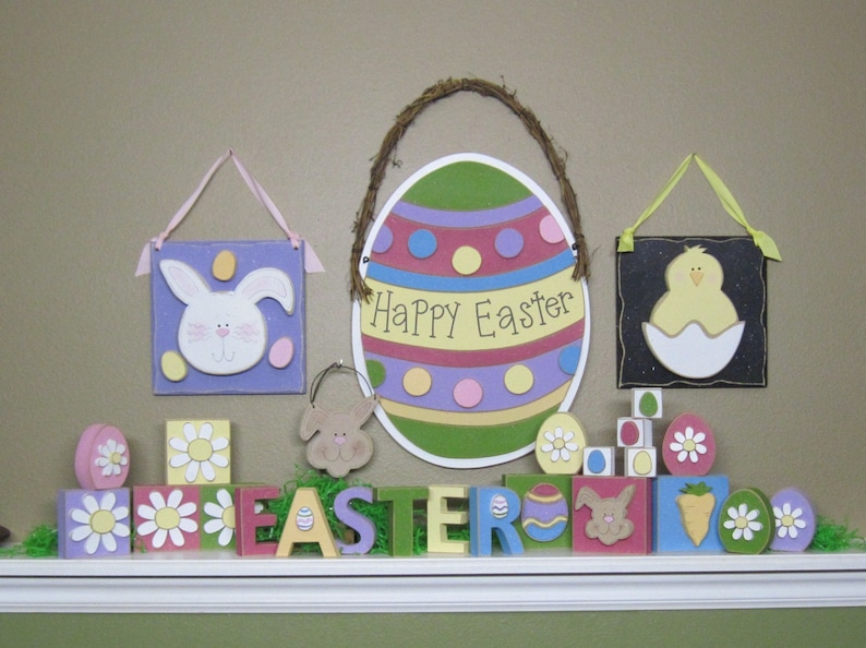 May include: A colorful Easter decoration with a large egg-shaped sign that says "Happy Easter" and a variety of wooden blocks with Easter-themed designs, including bunnies, chicks, and flowers.