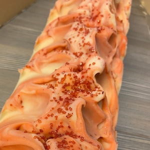 K&ouml;nnte beinhalten: Eine wei&szlig;e und rosafarbene Seife mit roten Zuckerkristallen darauf.