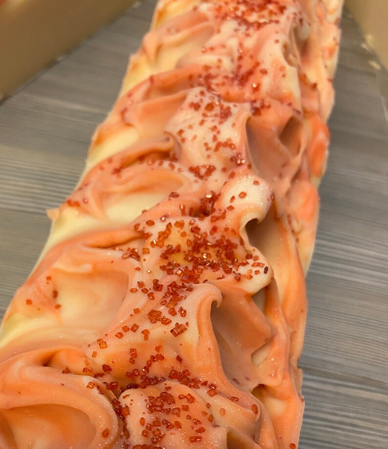 K&ouml;nnte beinhalten: Eine wei&szlig;e und rosafarbene Seife mit roten Zuckerkristallen darauf.
