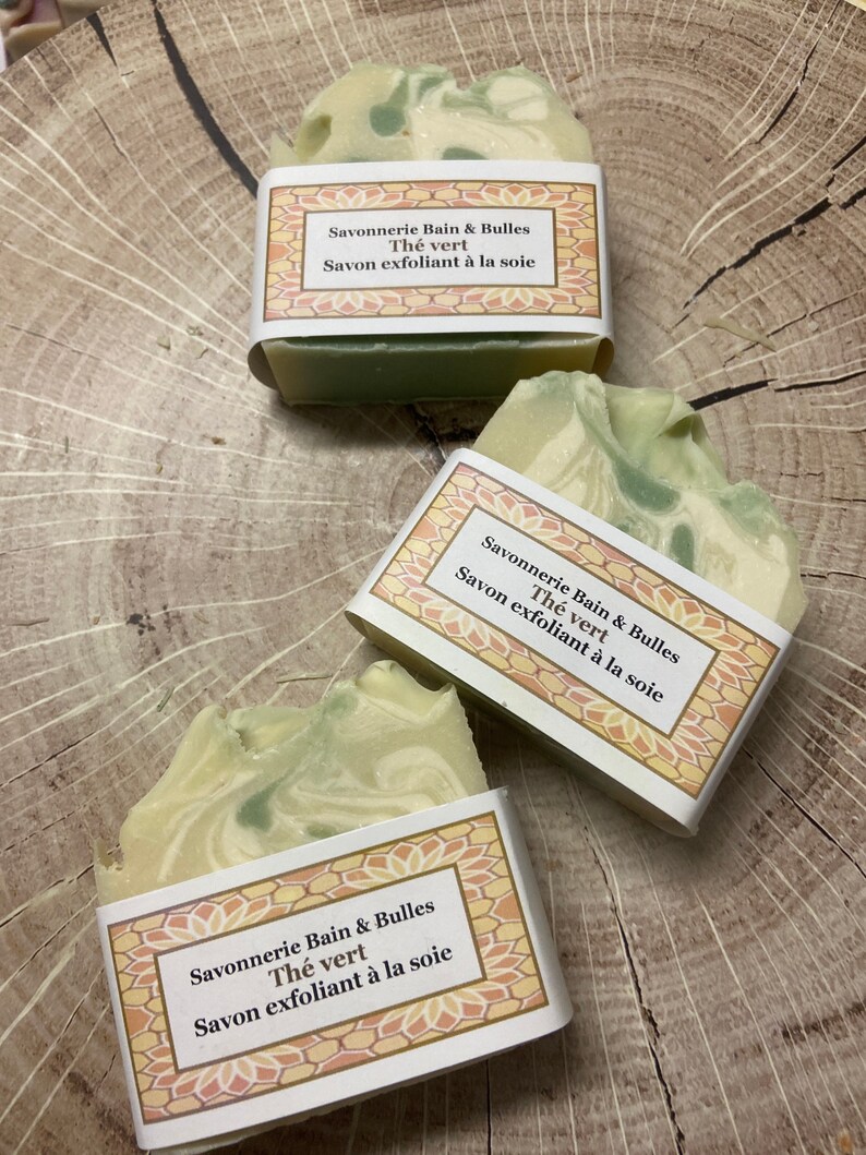May include: Three bars of green and white soap with a label that reads "Savonnerie Bain & Bulles Th&eacute; vert Savon exfoliant &agrave; la soie".