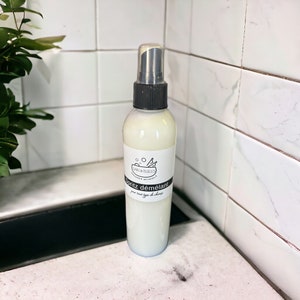 May include: A white plastic bottle with a black spray nozzle and a white label that says "Spritz démêlant" for all hair types. The bottle is on a white tiled surface.