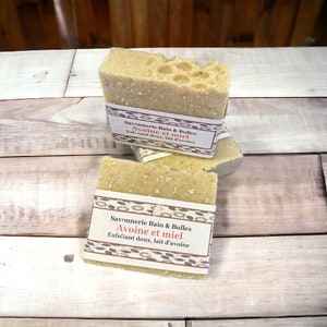 May include: Two bars of soap with a brown label that reads "Savonnerie Bain & Bulles Avoine et miel Exfoliant doux, lait d'avoine".