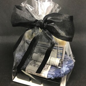 Puede incluir: Un set de regalo con una cinta negra y una bolsa de pl&aacute;stico transparente. El set incluye una pastilla de jab&oacute;n, una peque&ntilde;a botella de aceite esencial, una toallita y una peque&ntilde;a bolsa de sales de ba&ntilde;o. La etiqueta del jab&oacute;n dice "Bas &agrave; savon".